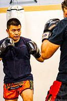 Photo showing two men sparring in boxing gloves and shorts, demonstrating boxing and Muay Thai training.