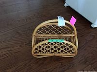 Front view of the bamboo magazine rack on a wooden floor showing lattice pattern and curved handle