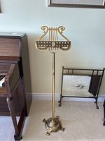 Full view of the brass lyre-shaped adjustable music stand, showing the decorative base and overall height.