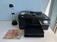 Overall lot showing HP Officejet 6600 printer, black desk lamp, and floral mouse pad on table.