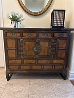 Front view of vintage Korean wood veneer cupboard with brass pulls and corner accents, showing 4 small upper drawers and 2 central cupboard doors with large brass lock plate and ring handles.