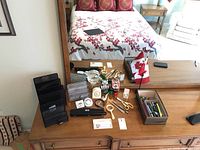 Top view of desk with various black metal mesh desk organizers, scissors, magnifying glasses, timers, Canadian flag, hole punch, and other office accessories arranged on the wooden surface in front of a large mirror.