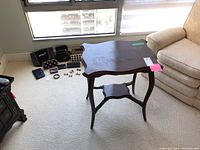 Side view of dark stained oak occasional table with scalloped edges and a lower open shelf. Shows surface wear and water marks on tabletop.