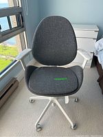 Front view of the grey upholstered office chair with white metal frame and caster wheels.