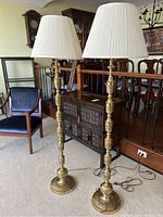 Full view of the pair of tall Korean brass floor lamps with white pleated shades in a living room setting, showing overall size and style.