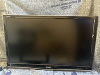 Front view of Sharp Aquos TV with black bezel and screen turned off.