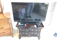 Sony 40-inch flatscreen TV displayed on dark ornate wooden TV stand, showing the television from the front with its screen reflecting the room, black bezel and Sony logo visible.