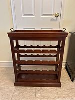 Front view of the dark wood wine rack showing four rows for bottle storage with scalloped bottle rests.