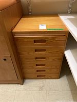 Front view of wooden pine set of drawers with six drawers showing wood grain and horizontal recessed handles.