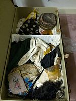 Trunk overview showing beaded purse, parasol, feather fan, hair comb, white boots, grey hat