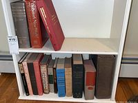 Two white shelves filled with various books including reference, literature, and vintage titles