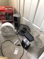 Photo showing Honeywell Warm Mist Humidifier box alongside various fans and a Rayovac lantern on carpet.