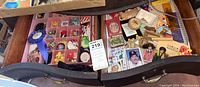 Drawer open showing an array of miniature toys, collectibles, badges, and novelties spread across and around compartmentalized containers.