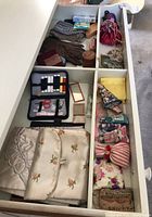 Top view of drawer showing gloves, sewing kit, sachet bags, and cosmetic cases in compartments