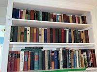 Shelf filled with 45 vintage hardcover books with varied titles and colors on three shelves.