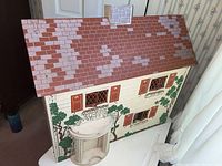 Front view of dollhouse showing painted brick roof and foliage detailing on exterior walls