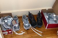 Four pairs of women's New Balance sneakers on floor, three grey size 8 and one dark size 9 visible