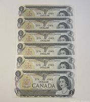 Eight 1973 Canadian 1 dollar bills arranged in sequence showing serial numbers