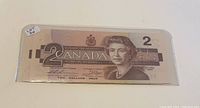 Stack of five Canadian $2 bills face up showing Queen Elizabeth II portrait and front design