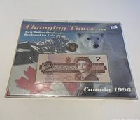 Photo showing the 1996 Canadian two dollar banknote and two dollar coin mounted on the presentation card with 'Changing Times ... Two Dollar Banknote Replaced by Coin' and a polar bear image.