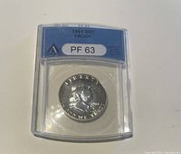 Obverse side of 1961 US 50 cent silver proof coin, showing the Liberty head design, date, and grading PF63 by ANACS.