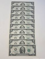 Photo of 10 sequential 2003 A $2 bills stacked front facing up, showing serial numbers in sequential order.