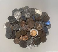 Pile of mixed US coins including pennies, nickels, dimes, and quarters showing variation in wear and color.