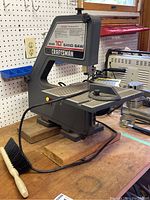 Sears Craftsman 10-inch band saw on wooden workbench, showing side view with power cord and yellow switch.
