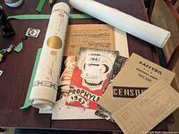 Overview of ephemera including rolled reproductions, printed leaflets including Daffydil and Freemason materials, and typeset documents on table