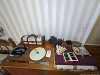 Table with assorted games, decorative boxes, vanity items, tall ship bookend, office supplies arranged