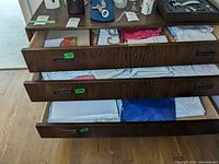 Three drawers partially opened showing assorted folded linens including plain and embroidered pieces.