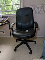 Front angle photo of a black padded rolling office chair with cushioned backrest, seat, black armrests, and caster wheels on a five-leg base.