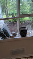 Window sill display showing all items: LL Bean Stabil-icers in plastic bag, vintage flower fasteners, black wicker flower pot, and glass vases.