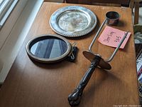 Photo showing all four sterling silver items: meat fork, napkin ring, round dish, and picture frame on wooden surface.