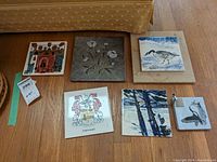 Overview of art tiles and soapstone pen holder showing six tiles on floor, various designs including bird and floral motifs and family crest.