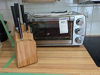 Oster toaster oven next to a Ginsu wooden knife block with knives inside.