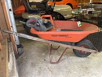 Photo showing the full wheelbarrow from the side, including taped wooden handle, and the Sears Power Blower resting inside the wheelbarrow.