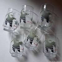 Set of six clear glass tumblers laid out on a flat surface showing the Inuit art design on each glass.