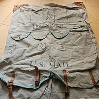 Full view of the wall organizer laid out flat showing canvas material, leather straps, stenciled text including 'U.S. MAIL' and numbered flap pockets.