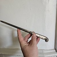 Photo of entire silver letter opener held in hand showing length and design.