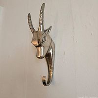 Metal ram head wall hook with two curved horns, silver finish, and single hook extension.