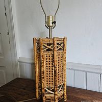 Full view of vintage wood and cane table lamp showing rectangular cane panels, wood frame, and brass socket.