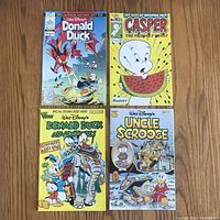 Four comic books arranged in two rows showing covers: Donald Duck Adventures, Casper the Friendly Ghost, another Donald Duck Adventures, and Uncle Scrooge.