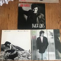 Front cover showing three Gino Vannelli LP records on wooden floor: Black Cars, Brother to Brother, and one partially visible album.