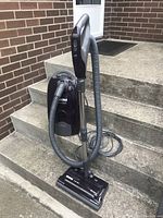 Full view of assembled canister vacuum with hose, wand and power nozzle on concrete steps