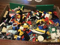Top view of a box filled with assorted LEGO bricks and parts in multiple colors.
