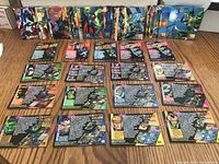 Photo of approximately 54 Marvel Universe trading cards laid out and stacked on a wooden surface, showing front colorful artwork and character images.