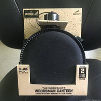 Photo showing front of black Hudson Line Woodsman Canteen in original cardboard packaging, highlighting 2 liter capacity and textile fabric