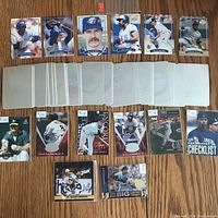 Three rows of sports cards laid flat, upper row predominantly Blue Jays baseball cards in plastic sleeves, middle row mixed cards including MLB holograms and others, bottom row showcasing various single cards including Ken Griffey Jr. checklist card.