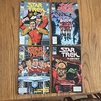 Four Star Trek comics laid out on a wood surface, showing covers with characters and starship Enterprise